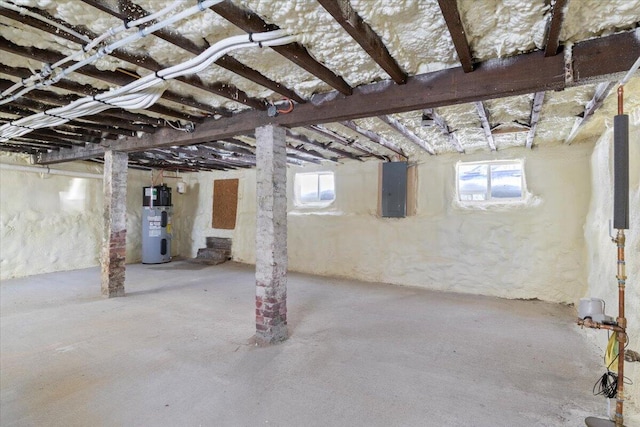 basement featuring electric panel, a wealth of natural light, and electric water heater