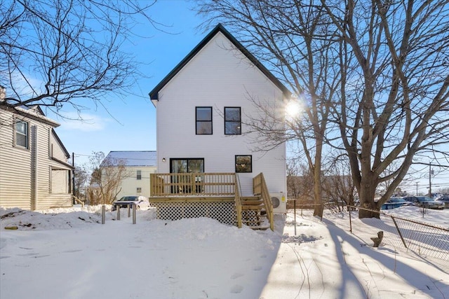 snow covered rear of property featuring fence and a deck