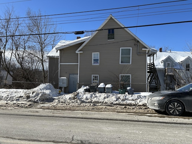 view of snowy exterior featuring stairway and a chimney