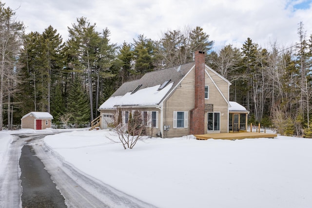 exterior space featuring an outbuilding, an attached garage, a chimney, and a storage shed