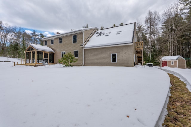 snow covered property featuring stairs, a storage unit, and an outdoor structure