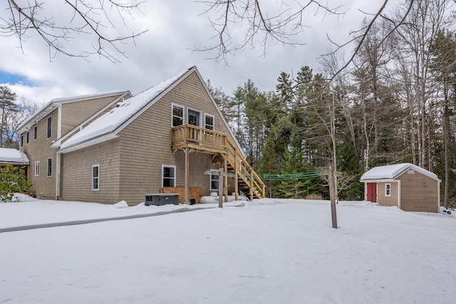 snow covered property with a storage shed, stairway, and an outdoor structure