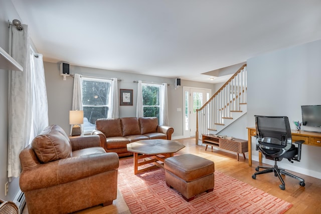 living area featuring light wood-style flooring, stairs, baseboards, and baseboard heating