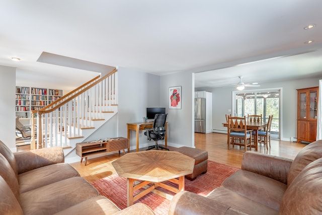 living room featuring recessed lighting, baseboard heating, light wood-type flooring, baseboards, and stairs