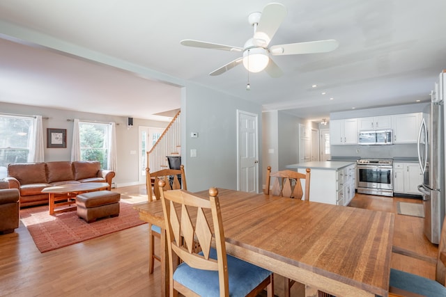 dining room with light wood-style floors, ceiling fan, stairway, and recessed lighting