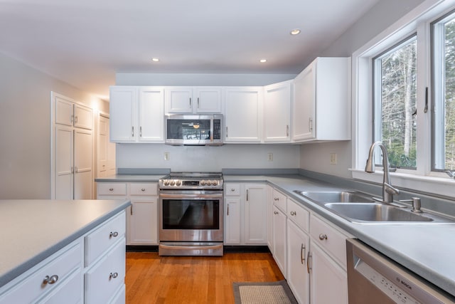 kitchen with stainless steel appliances, a sink, and white cabinetry