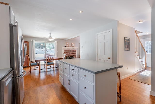 kitchen featuring light wood finished floors, white cabinetry, a kitchen bar, and appliances with stainless steel finishes