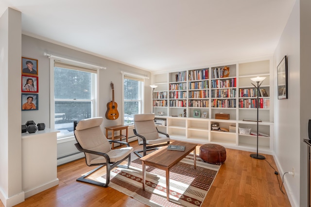 living area with a baseboard radiator, baseboards, and wood finished floors