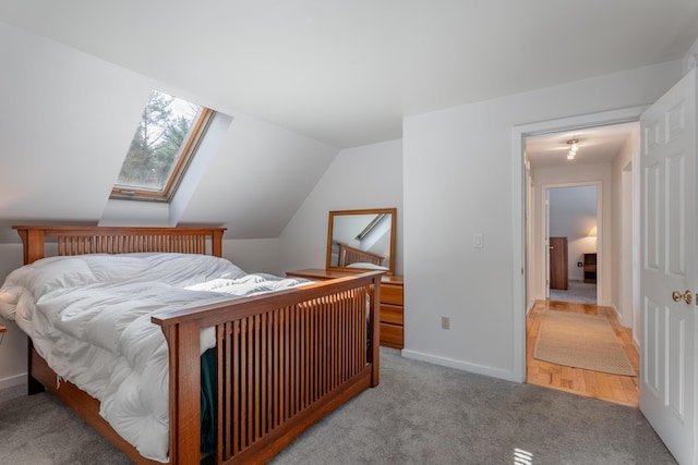 bedroom featuring carpet floors, lofted ceiling with skylight, and baseboards