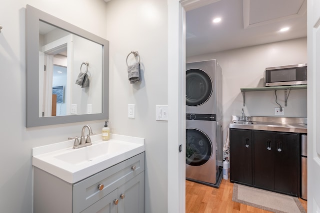 interior space featuring stacked washing maching and dryer, wood finished floors, vanity, and recessed lighting