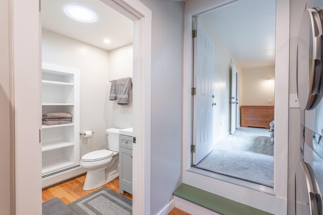 bathroom with vanity, baseboard heating, wood finished floors, and toilet