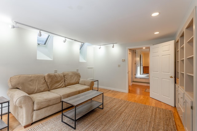 living room with a skylight, recessed lighting, track lighting, light wood-type flooring, and baseboards