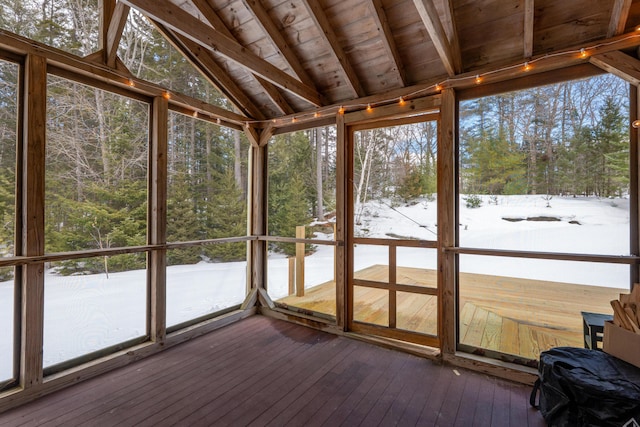 unfurnished sunroom featuring wooden ceiling, a healthy amount of sunlight, and lofted ceiling with beams