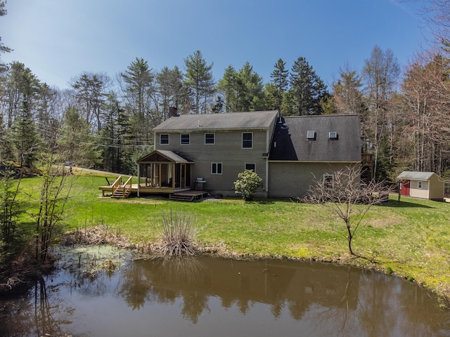 27 Libby Ln, Brunswick, ME 04011 - rear view of house featuring an outdoor structure, a deck with water view, a storage unit, a yard, and a chimney
