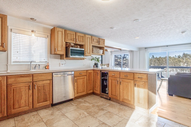 kitchen with beverage cooler, a peninsula, stainless steel dishwasher, and light countertops