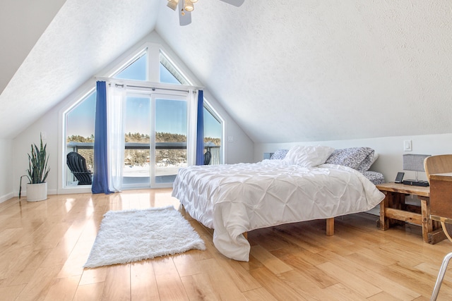 bedroom with light wood-style floors, access to outside, multiple windows, and a textured ceiling