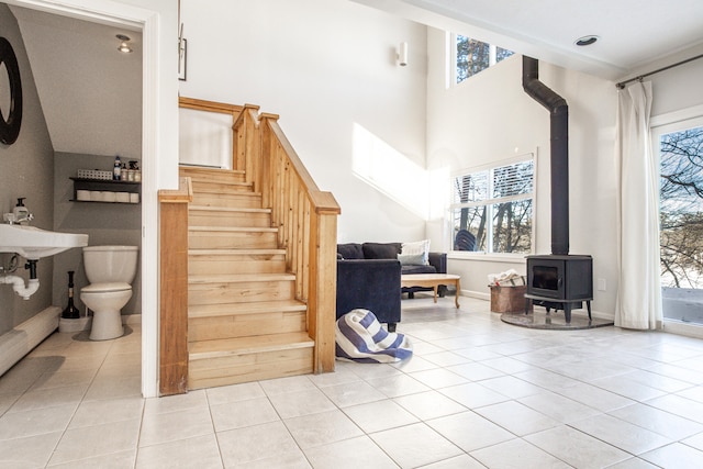 stairs featuring tile patterned flooring, a wood stove, a healthy amount of sunlight, and baseboards
