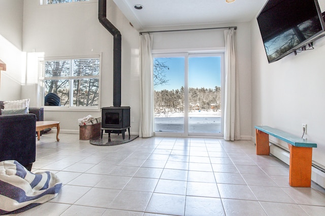 living area featuring plenty of natural light, light tile patterned flooring, and a wood stove