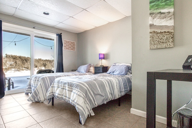tiled bedroom with access to outside, a drop ceiling, and baseboards