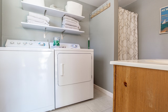 laundry room with laundry area, light tile patterned flooring, washing machine and clothes dryer, and baseboards