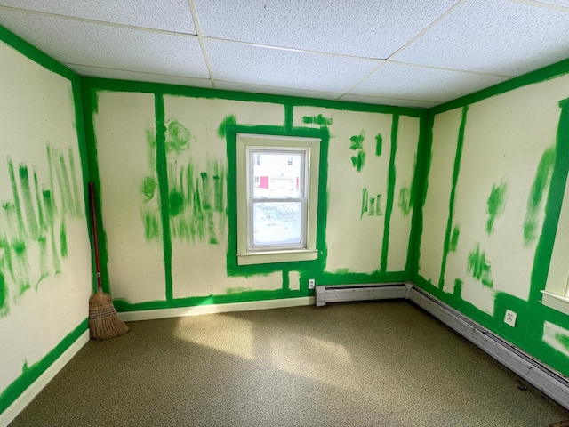 empty room with carpet floors, a paneled ceiling, and baseboards