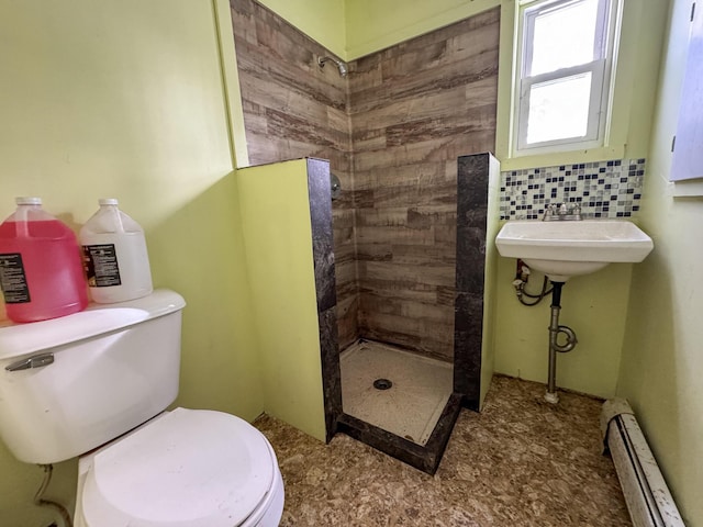 full bathroom featuring a stall shower, toilet, a baseboard radiator, a sink, and backsplash