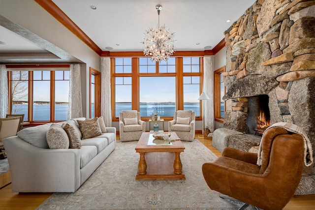 living room with ornamental molding, a fireplace, a water view, and wood finished floors