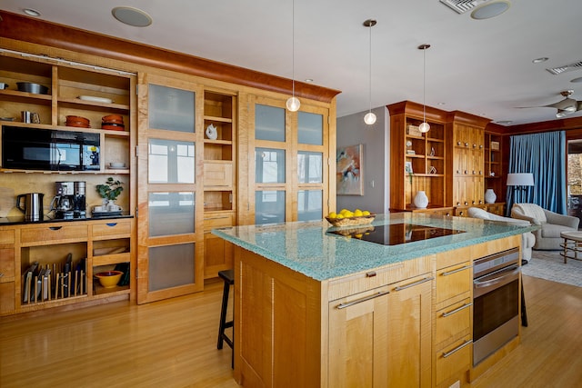 kitchen featuring light wood-type flooring, visible vents, a kitchen breakfast bar, and black appliances