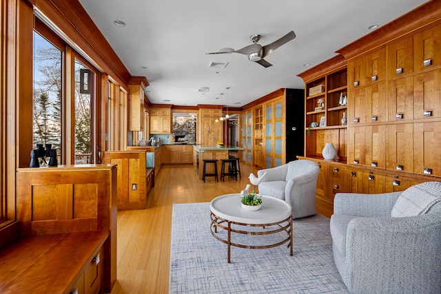 living room featuring light wood-style floors, visible vents, and a ceiling fan