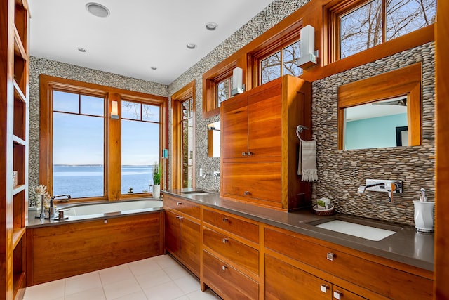 bathroom with a water view, a sink, backsplash, and a garden tub