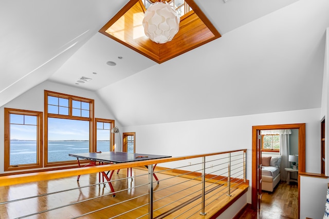 additional living space featuring lofted ceiling, a water view, wood finished floors, and visible vents