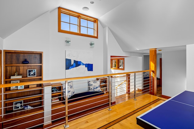 corridor featuring vaulted ceiling, wood finished floors, and an upstairs landing