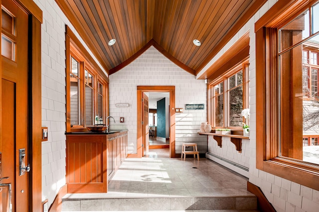 interior space featuring baseboard heating, a sink, vaulted ceiling, wooden ceiling, and tile patterned floors