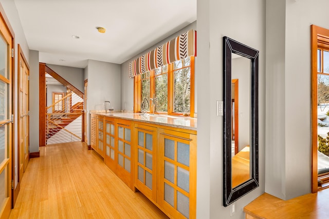 corridor with stairs, light wood finished floors, and plenty of natural light