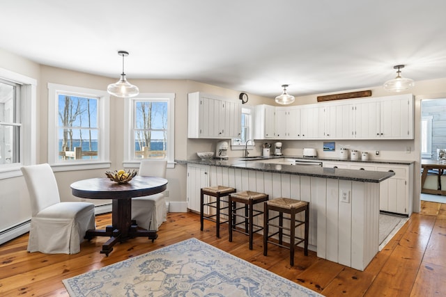 kitchen with light wood-style floors, white cabinets, a sink, and a peninsula