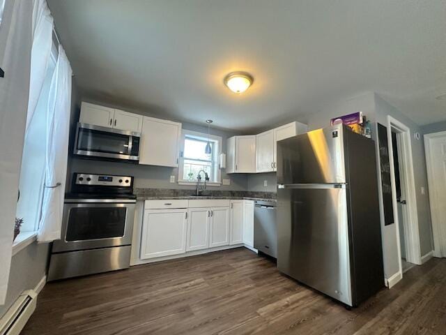 kitchen with white cabinets, dark countertops, a baseboard heating unit, and stainless steel appliances