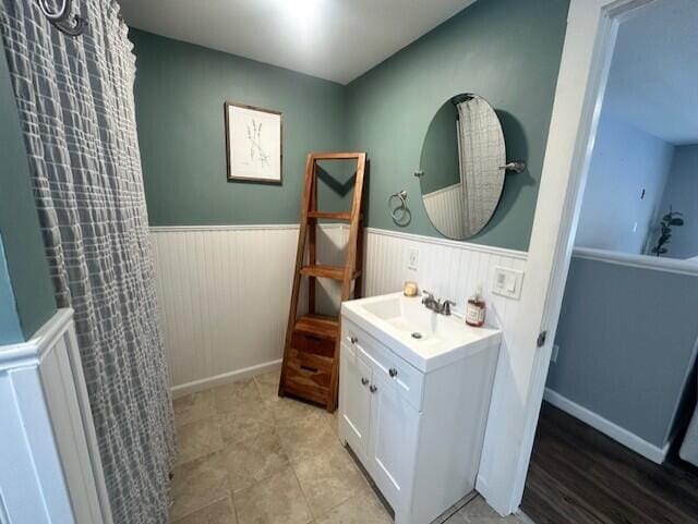 bathroom featuring curtained shower, vanity, and wainscoting