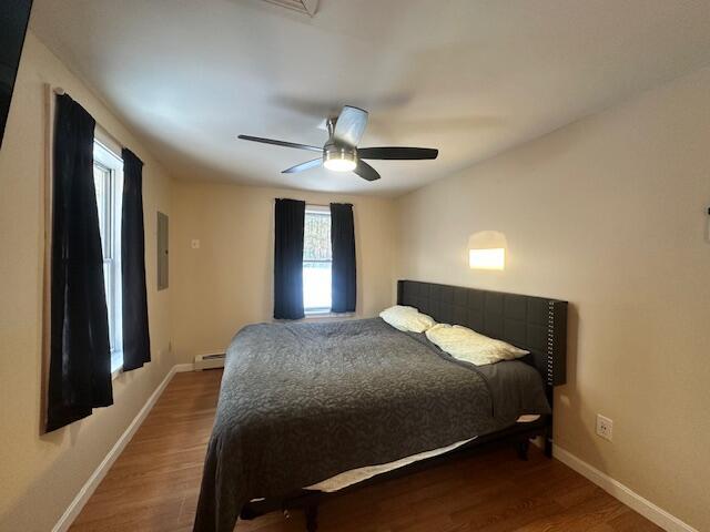 bedroom featuring a baseboard radiator, baseboards, and wood finished floors