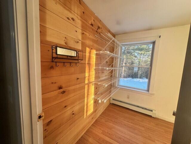 interior space with a baseboard radiator, wooden walls, and wood finished floors