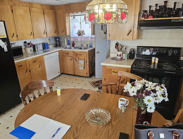 kitchen with light floors, light countertops, under cabinet range hood, and black appliances