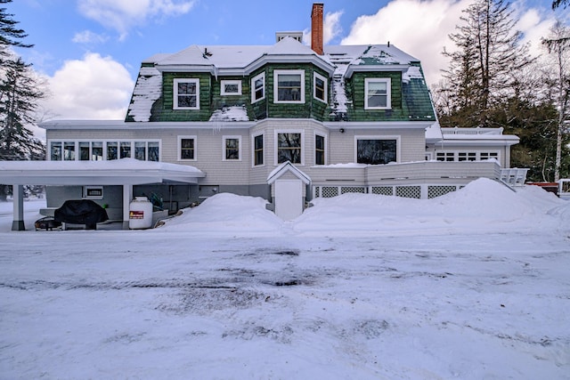 snow covered rear of property with a chimney