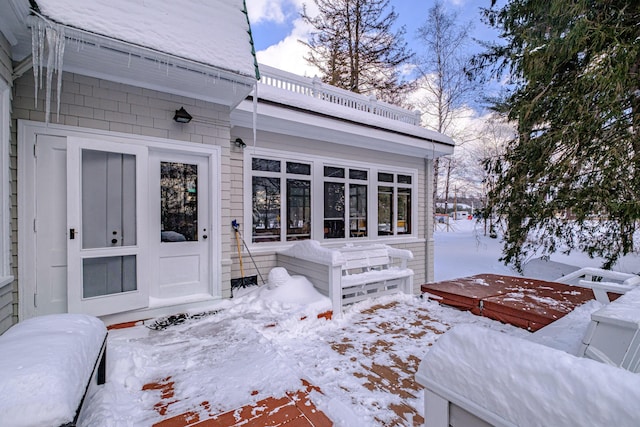 snow covered property entrance featuring a hot tub