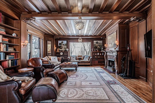 living room featuring a fireplace with flush hearth, a chandelier, wooden walls, and wood finished floors