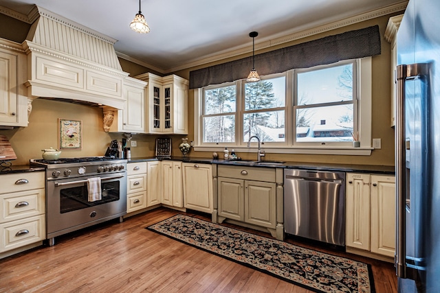 kitchen with hanging light fixtures, high end appliances, dark countertops, and glass insert cabinets