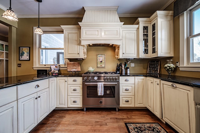 kitchen with ornamental molding, glass insert cabinets, high end stainless steel range, light wood-style floors, and pendant lighting