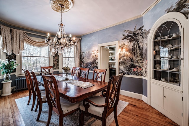 dining space featuring a notable chandelier, crown molding, baseboards, and wood finished floors