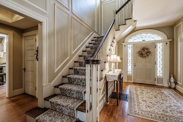 foyer entrance featuring dark wood finished floors, stairway, and baseboards