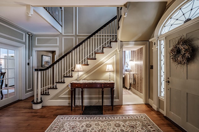 foyer with baseboards, stairway, a decorative wall, and wood finished floors