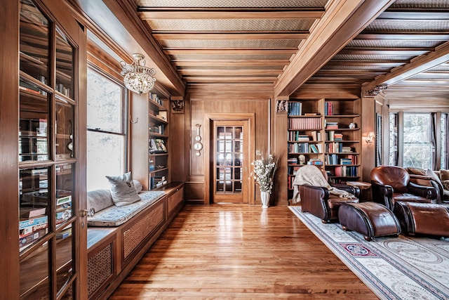 sitting room featuring beamed ceiling, an inviting chandelier, wood finished floors, and built in features