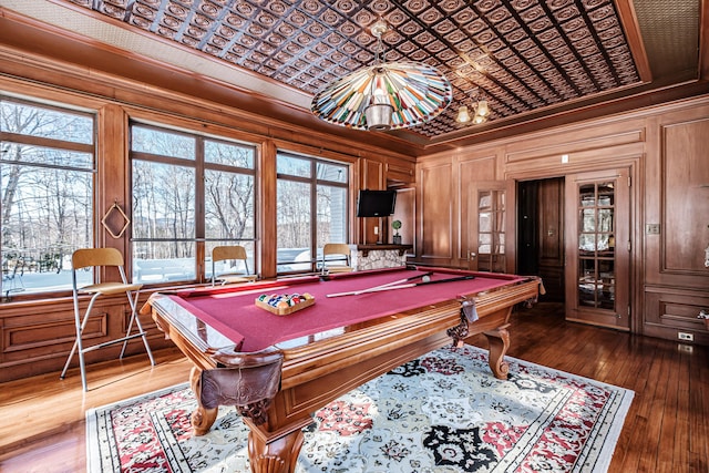 rec room with an ornate ceiling, wooden walls, ornamental molding, and dark wood-style flooring